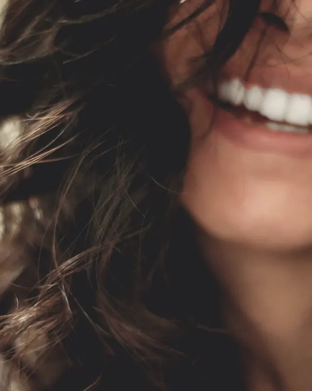 A woman laughing freely, her hair loose across her face